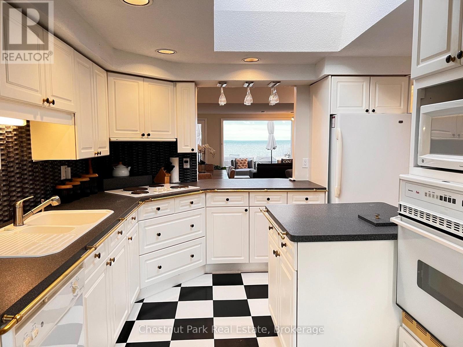 A kitchen with white cabinets and a black and white checkered floor.