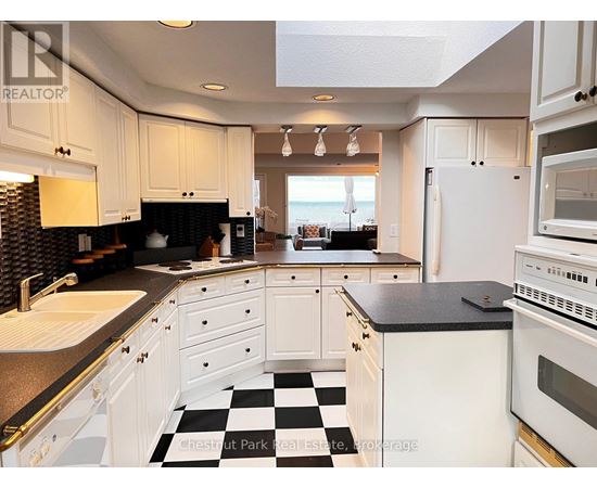 A kitchen with white cabinets and a black and white checkered floor.
