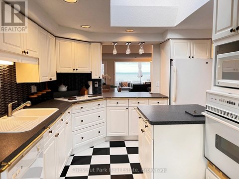 A kitchen with white cabinets and a black and white checkered floor.