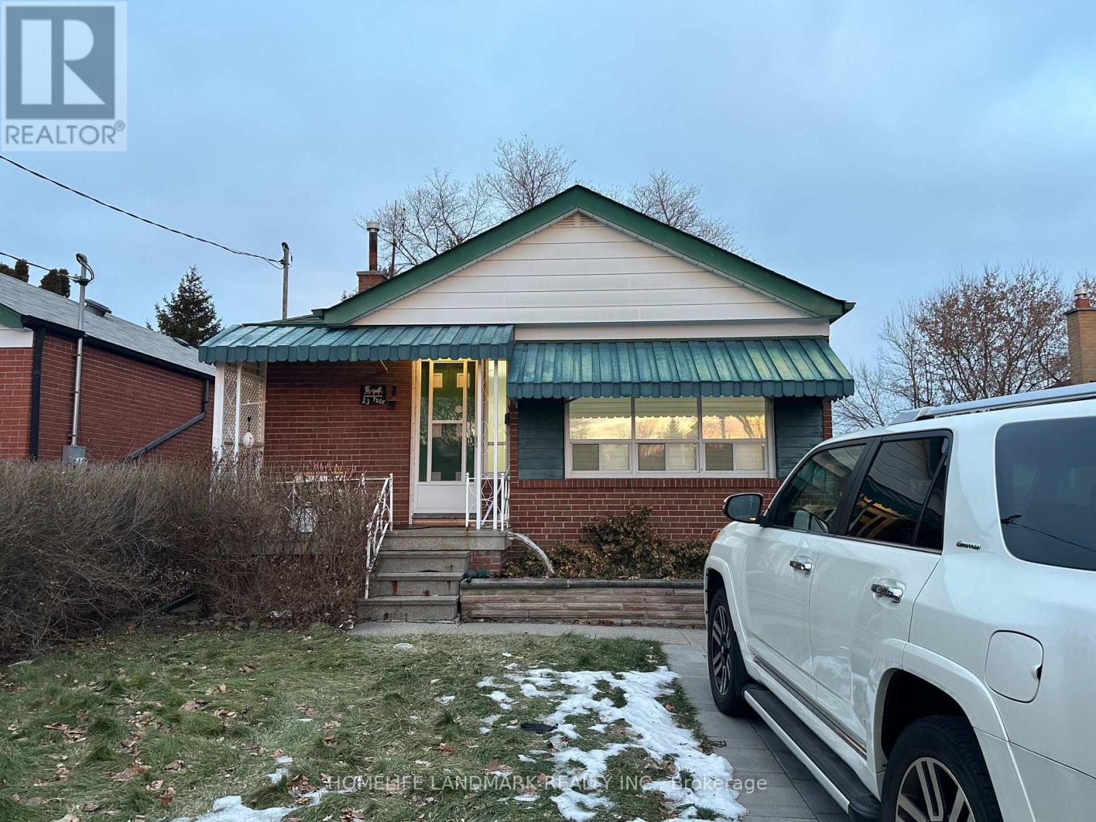A white SUV is parked in front of a house with a green awning.