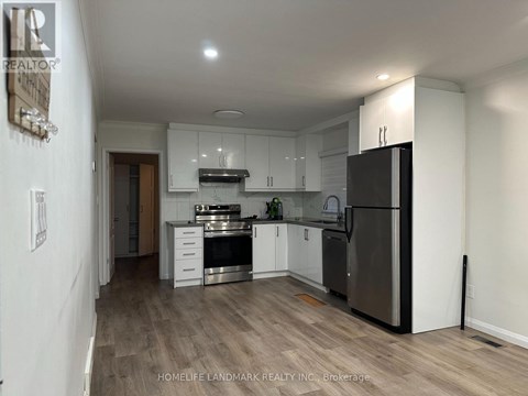 A kitchen with white cabinets and a black fridge.