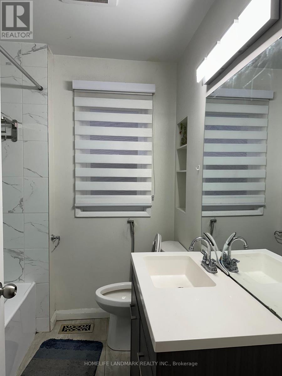 A bathroom with a sink, toilet and a window with blinds.