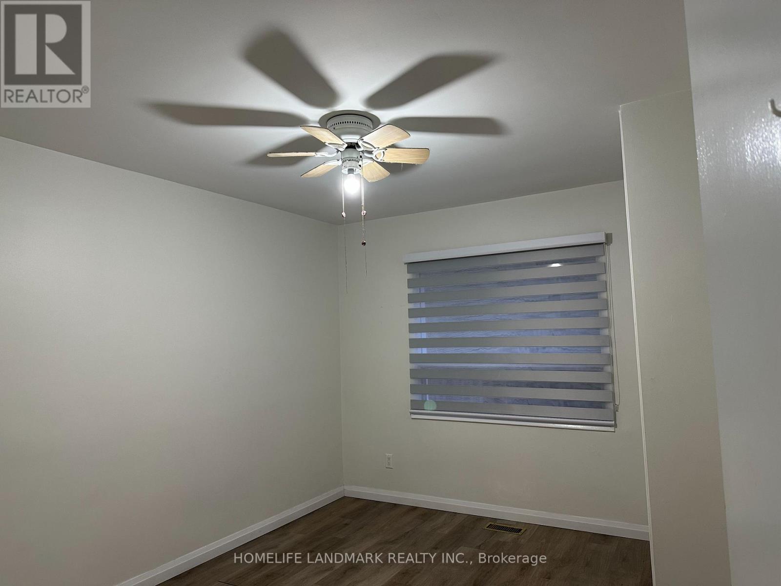 A room with a ceiling fan and a window with blinds.