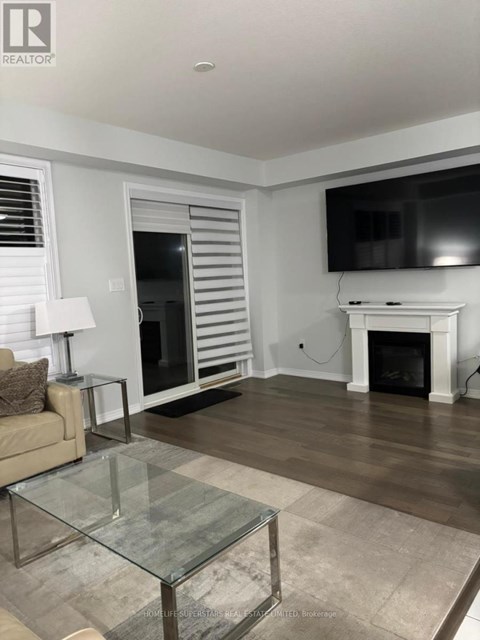 A living room with a glass coffee table and a fireplace.