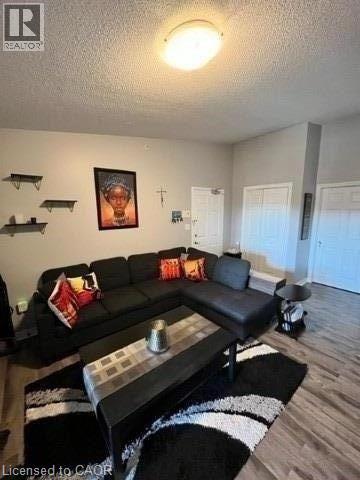 A black couch with a red pillow is in the middle of a living room.