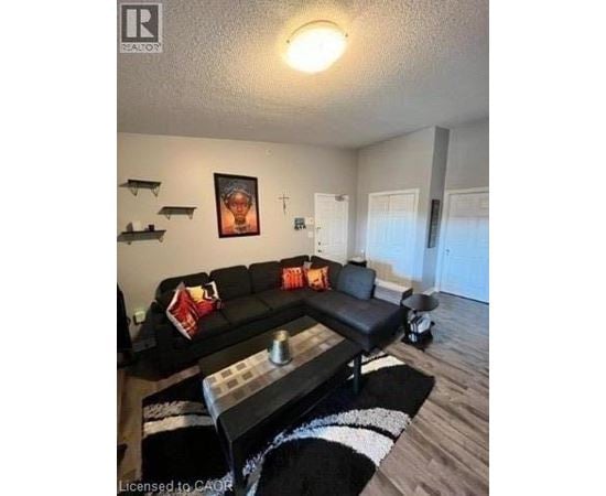 A black couch with a red pillow is in the middle of a living room.