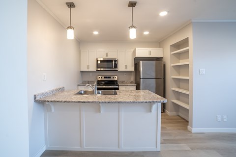 A kitchen with a granite countertop and stainless steel appliances.