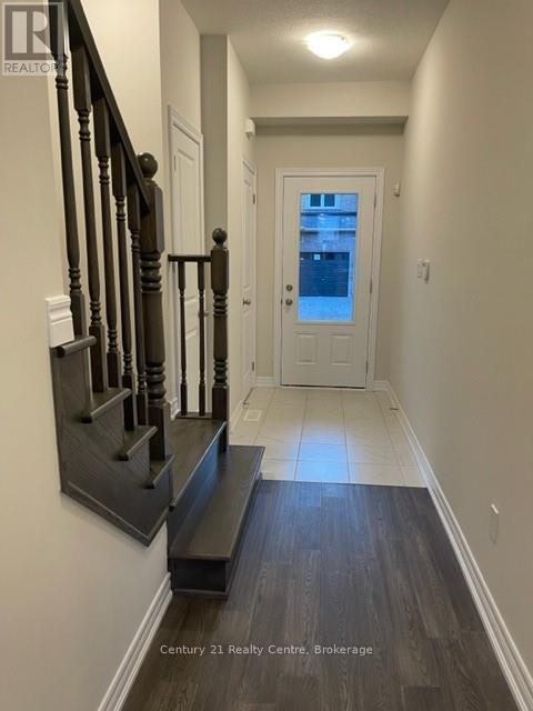 A hallway with a wooden staircase and a white door.
