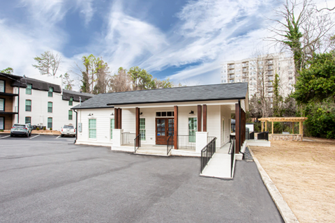 A building with a black roof and white walls is surrounded by a parking lot.