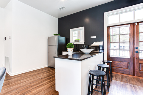 A kitchen with a black refrigerator and white countertops.