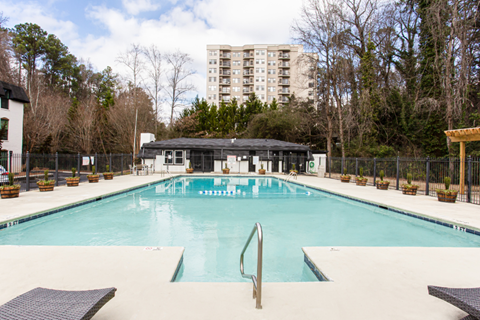 A large swimming pool with a diving board and a building in the background.