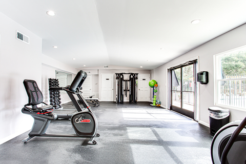 A home gym with a treadmill, exercise bike, and weights.