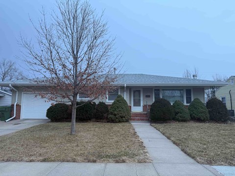 A house with a bare tree in front.