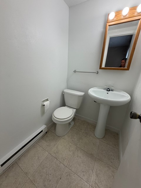 A bathroom with a toilet, sink, and mirror.