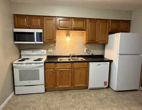 A kitchen with white appliances and wooden cabinets.