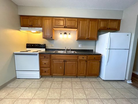 A kitchen with a white refrigerator, white oven, and wooden cabinets.