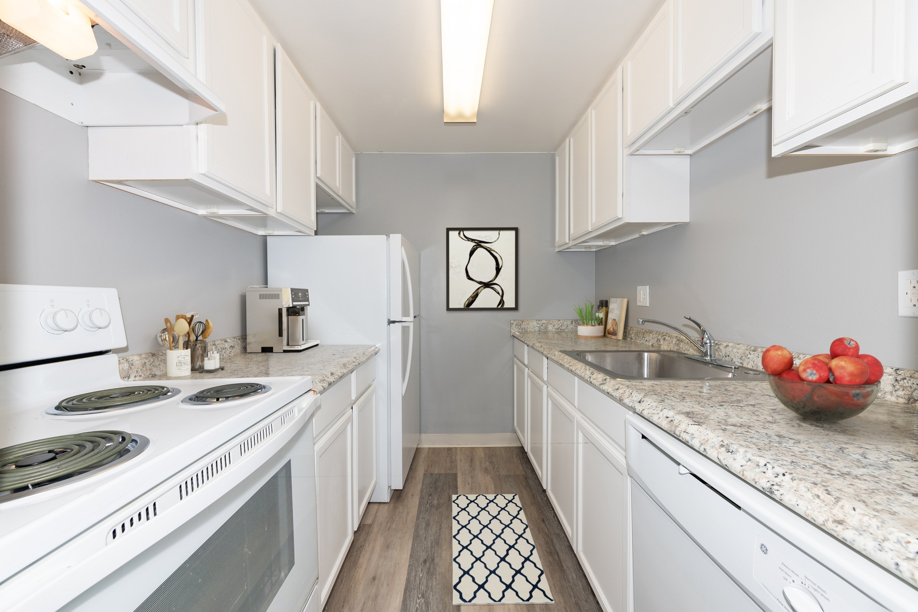 A kitchen with white cabinets and a white stove top oven.