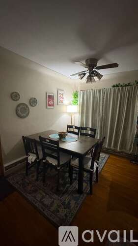 A dining room with a table set for two and a ceiling fan.