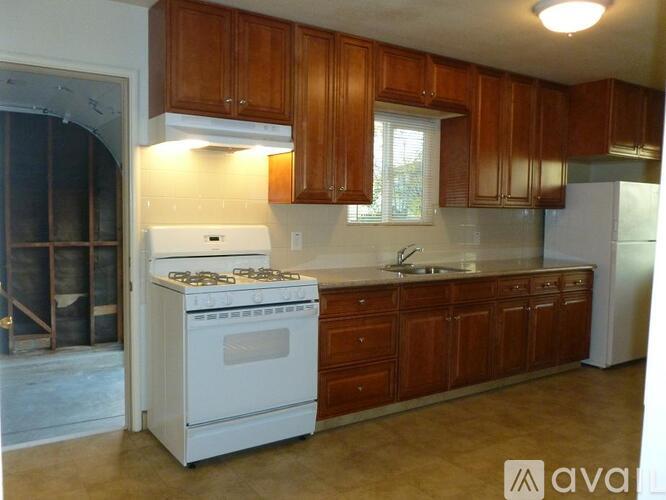 A kitchen with wooden cabinets and a white stove top oven.