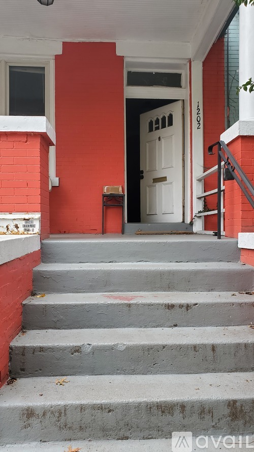 A set of stairs leading to a white door with a red wall on either side.