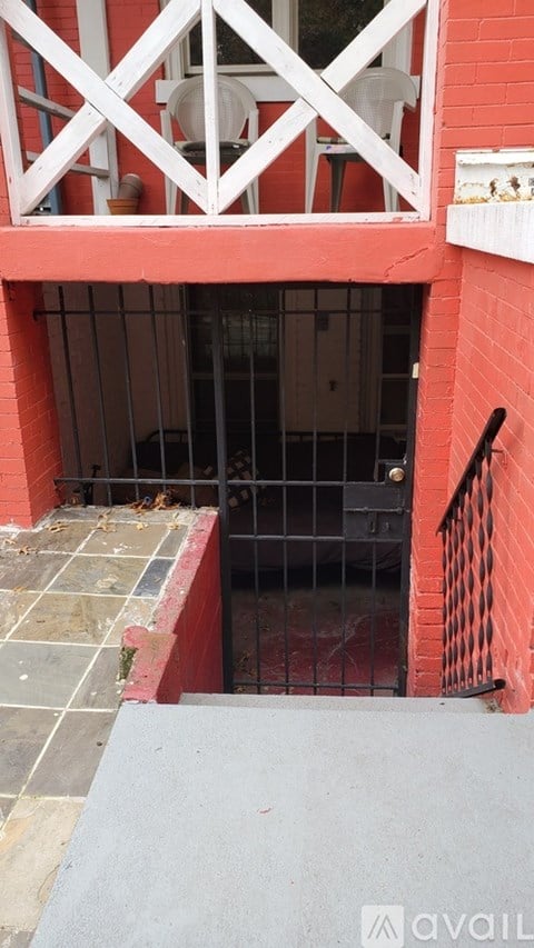 A set of stairs leading to a white door with a red wall on either side.
