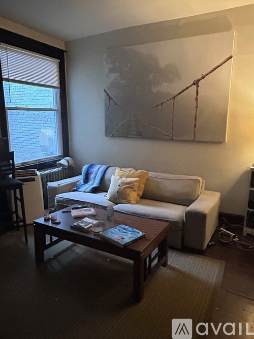 A living room with a white couch, a coffee table, and a painting on the wall.
