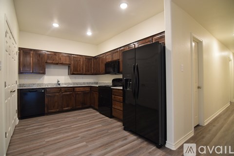 A kitchen with wooden cabinets and a black refrigerator.