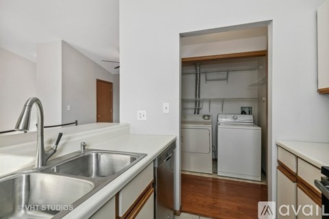 A kitchen with a sink and a washer and dryer in the background.