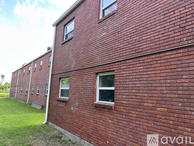 A red brick building with windows and a grassy area in front.