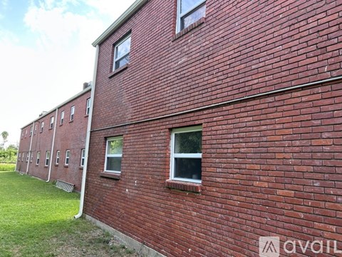A red brick building with windows and a grassy area in front.