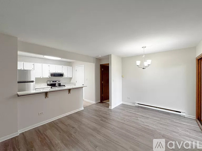 A spacious room with wooden flooring and a kitchenette in the corner.