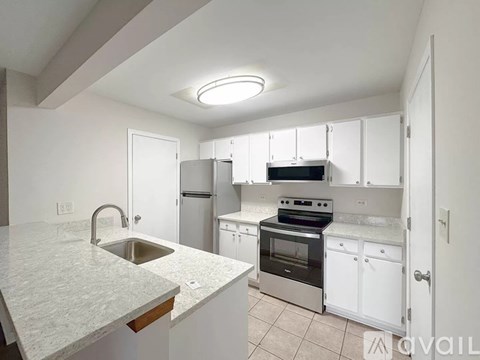 A kitchen with white cabinets and a marble countertop.