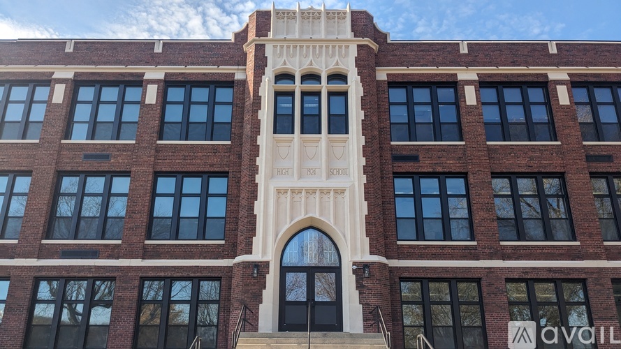 A large red brick building with a white arched entrance and a sign that says "AVAILABLE".