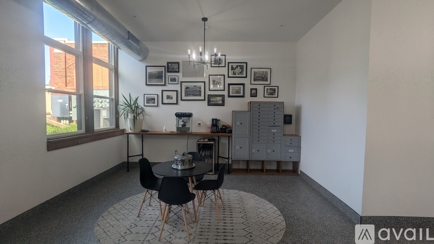 A room with a table and chairs in the center, a cabinet to the right, and pictures on the wall.