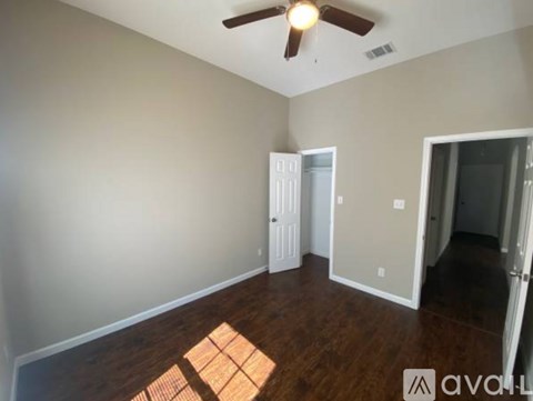 A room with a ceiling fan and wooden floors.