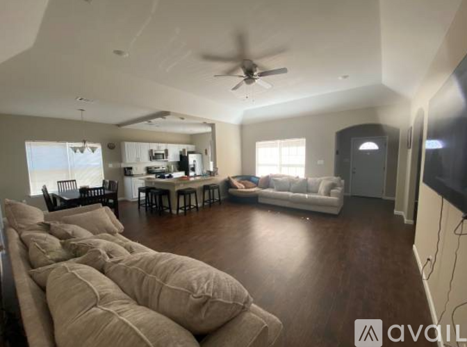 A living room with a couch, chairs, and a television.