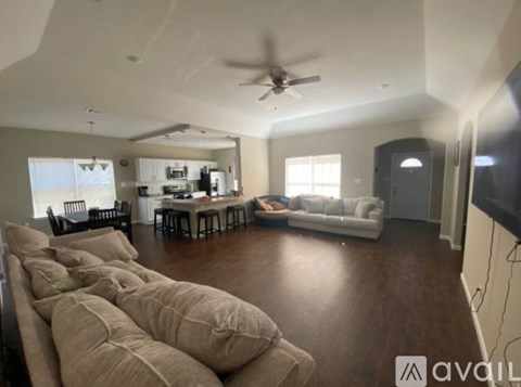 A living room with a couch, chairs, and a television.