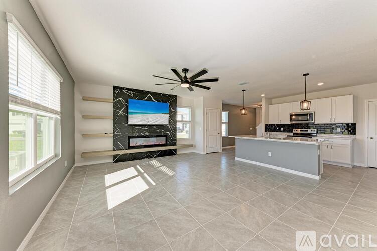 A spacious living room with a large television and a marble fireplace.