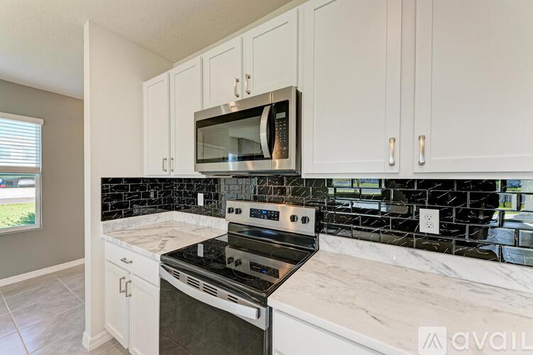 A kitchen with white cabinets and a black stove top.