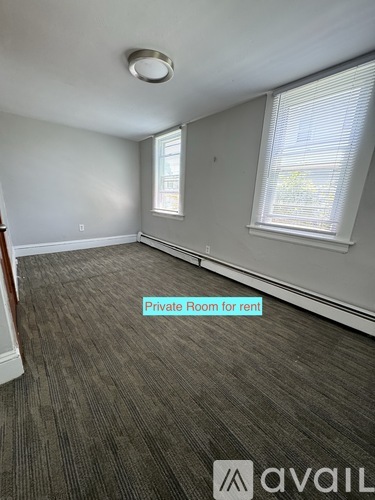 A room with a carpeted floor and a window with blinds.