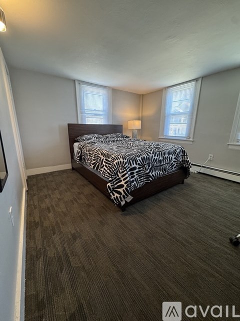 A room with a carpeted floor and a window with blinds.