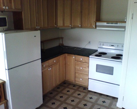 A kitchen with white appliances and wooden cabinets.
