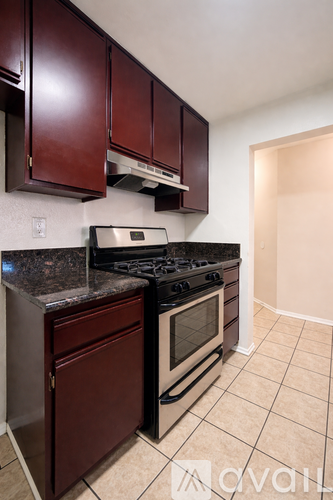 A kitchen with dark brown cabinets and a black stove top oven.