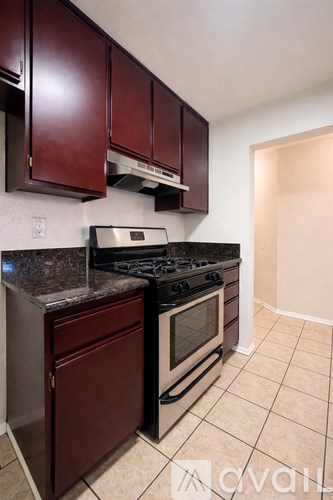 A kitchen with dark brown cabinets and a black stove top oven.