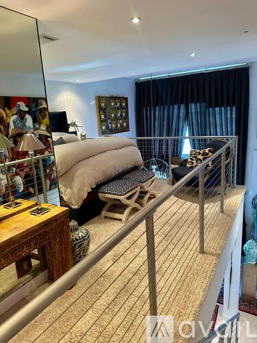 A bedroom with a bed, a chair, and a table with a lamp on it.