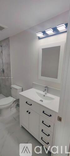 A bathroom with a toilet, sink, and mirror.