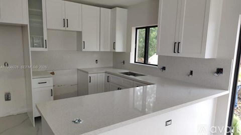 A modern kitchen with white cabinets and a large island.