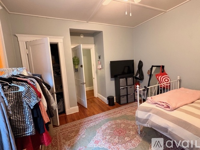 A bedroom with a bed, a TV, and a closet with clothes.