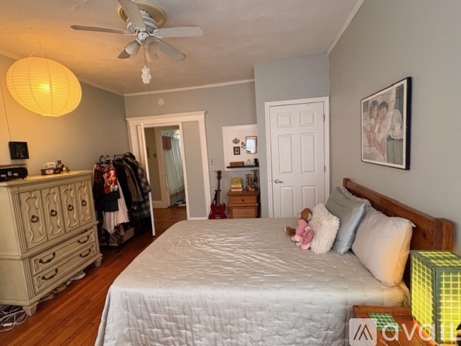 A bedroom with a large bed, a dresser, and a ceiling fan.