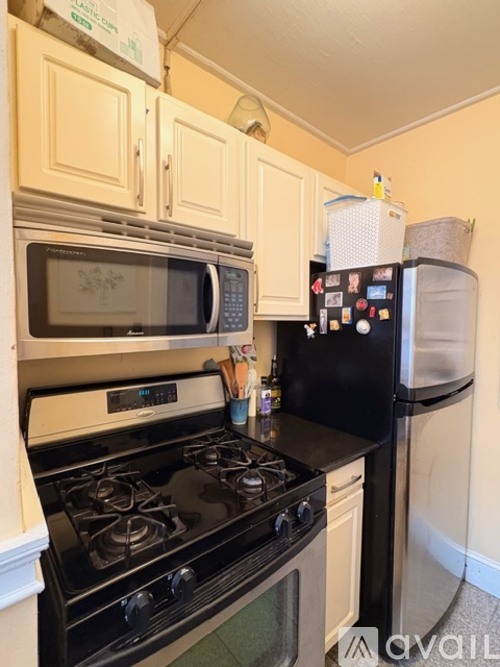 A kitchen with a black stove top oven and a black refrigerator with a white door.